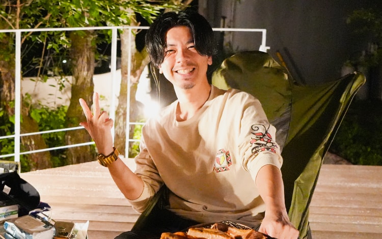 夜の屋外デッキで笑顔でピースする男性